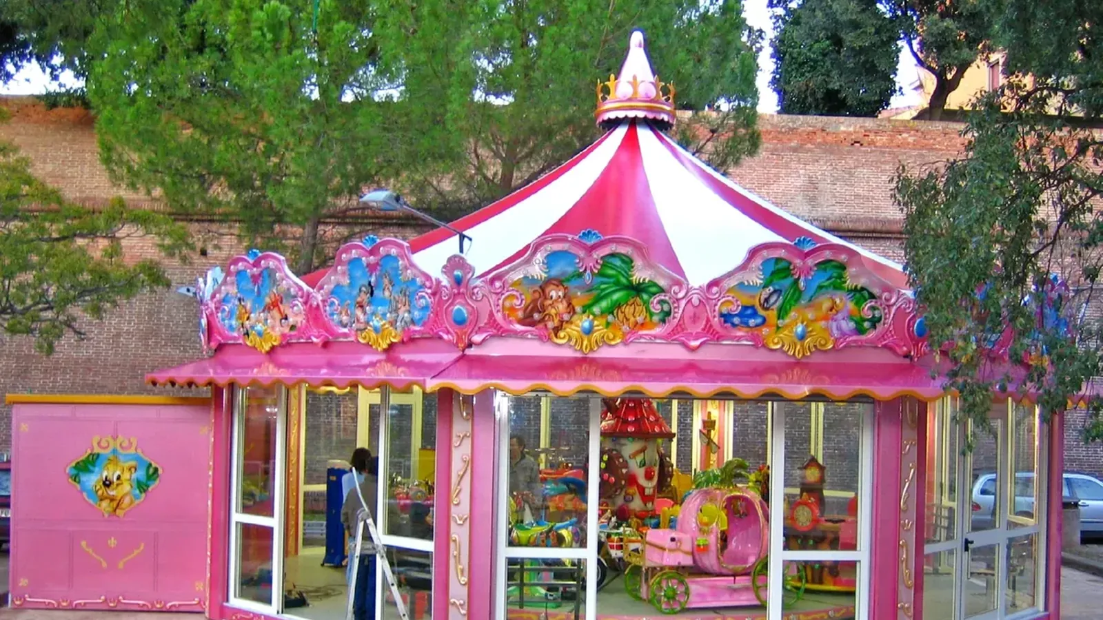 A themed kiddie carousel with indoor-style canopy in an outdoor park